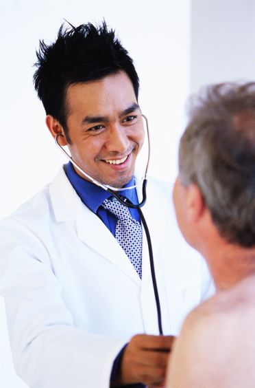 Doctor joven auscultando a un paciente